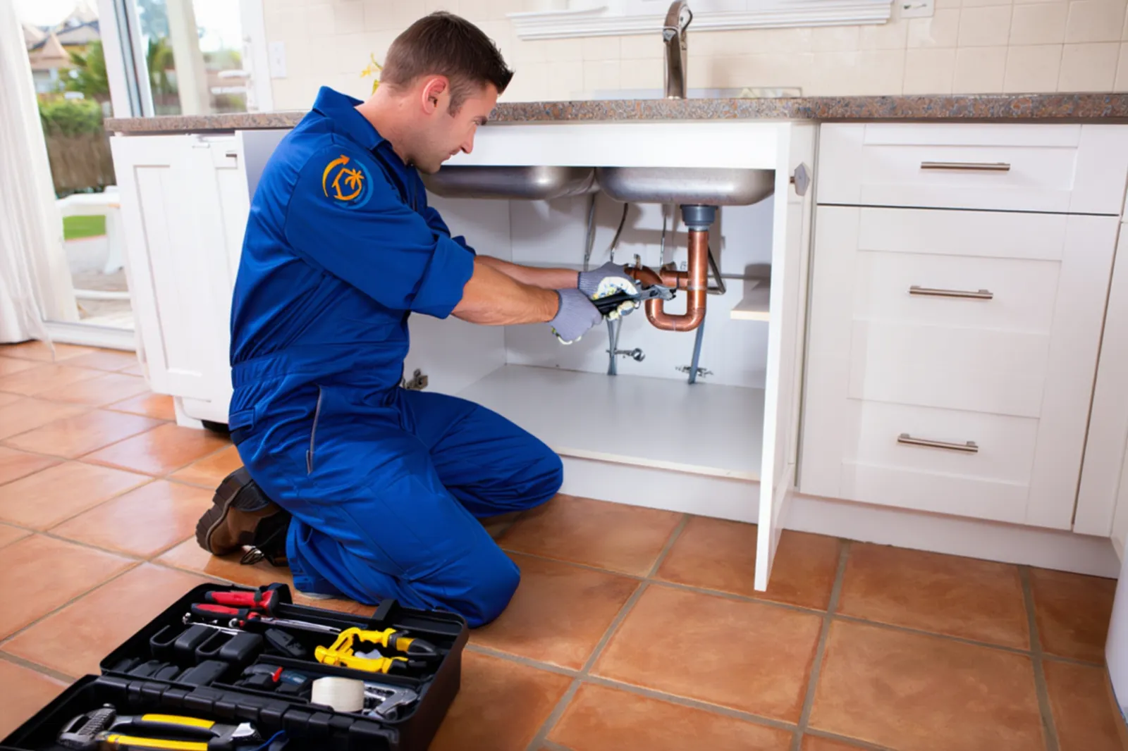 Idraulico che ripara tubature sotto il lavandino in appartamento a Fuerteventura
